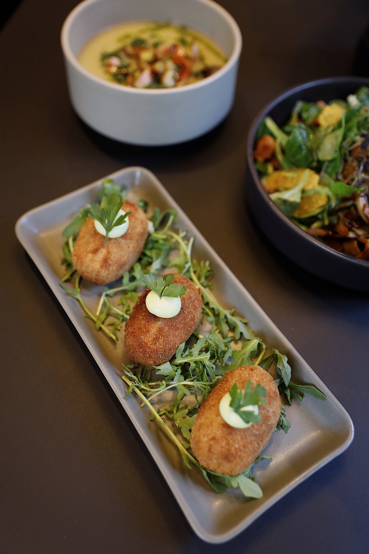 Platte mit drei Kroketten und Salat